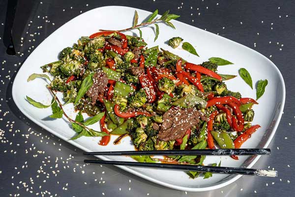 Das Wokgemüse mit Wagyu Filet Streifen auf einem großen Teller
geben und anschließend mit weißem Sesam und japanischem Koriander servieren.