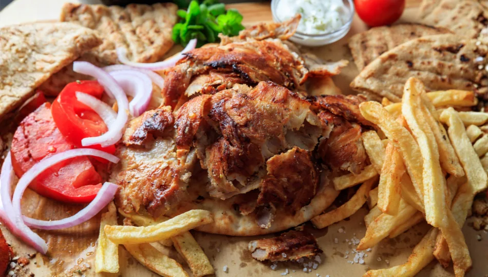 Dünne Streifen Schweinefleisch in einer Schüssel mit selbstgemachter, kräuterreicher Gyros-Marinade aus Olivenöl und Knoblauch