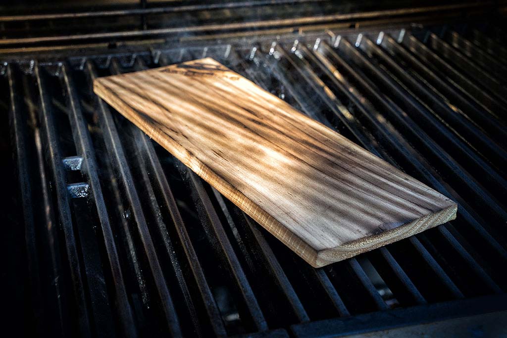 Zedernholz-Planke auf Grillrost legen, bis sie raucht und knackt.