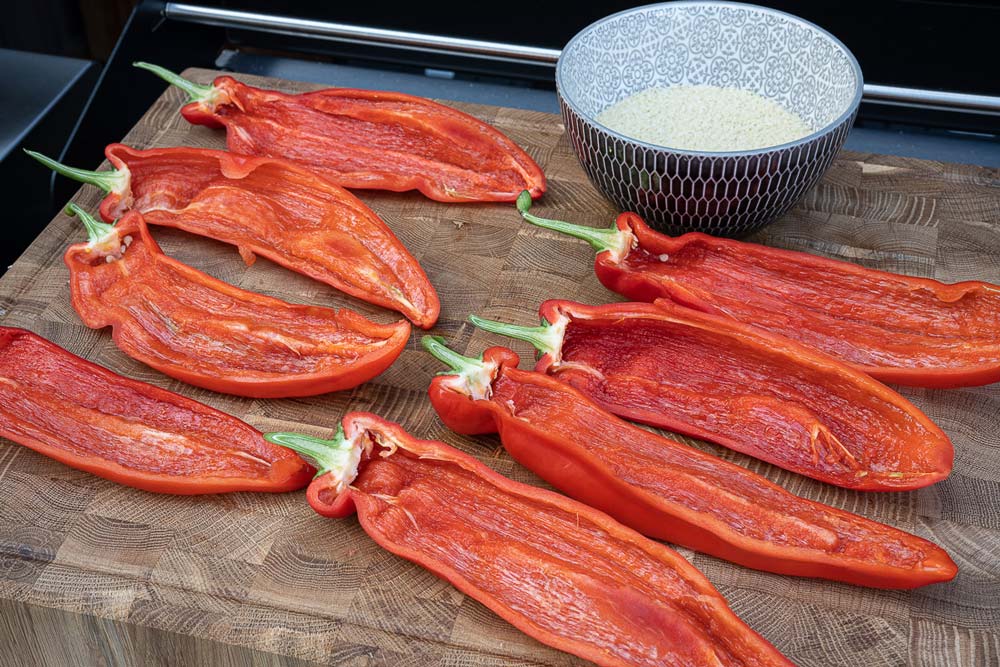 Die Spitzpaprika unter fließendem Wasser waschen, mit einem Küchentuch trocken tupfen,
längs teilen und entkernen. Den Couscous mit heißem Wasser aufgießen.
