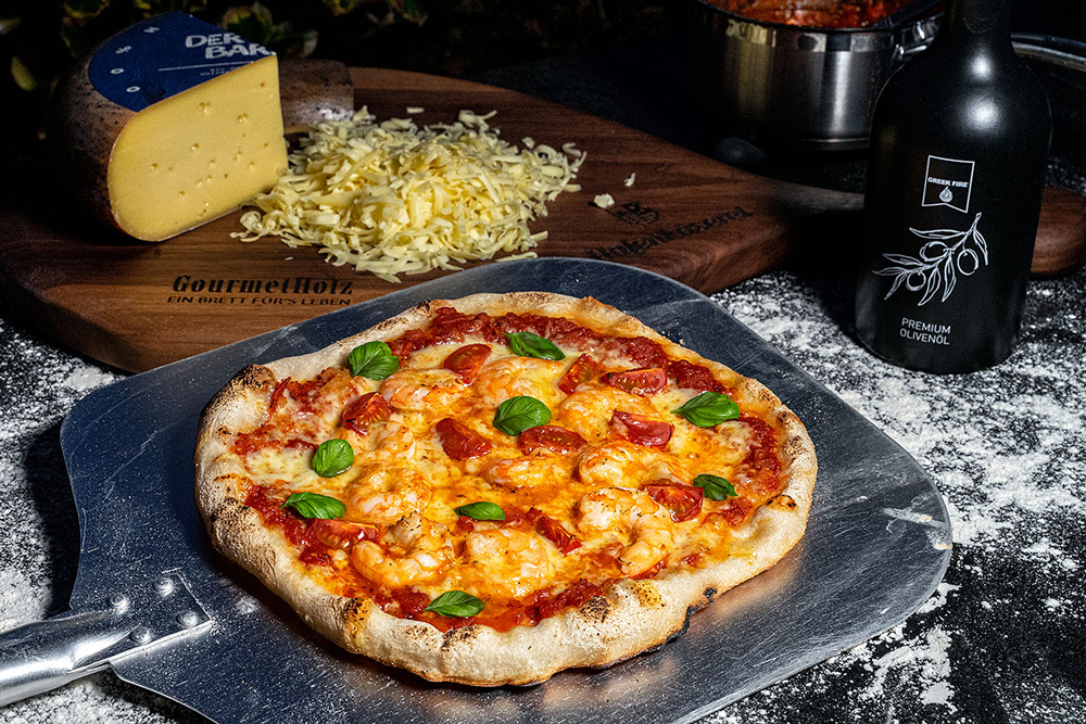 Pizza mit frischem Basilikum belegen. Das gibt einen tollen Geschmack und ein buntes Bild.