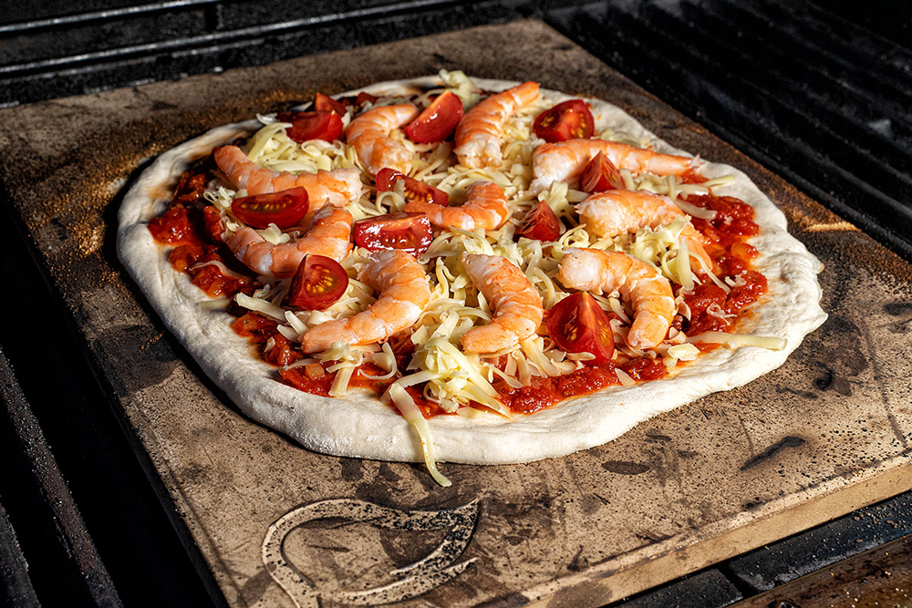 Mit Tomatensauce, Tomaten, Garnelen und Käse belegen. 4 bis 5 Minuten backen. 