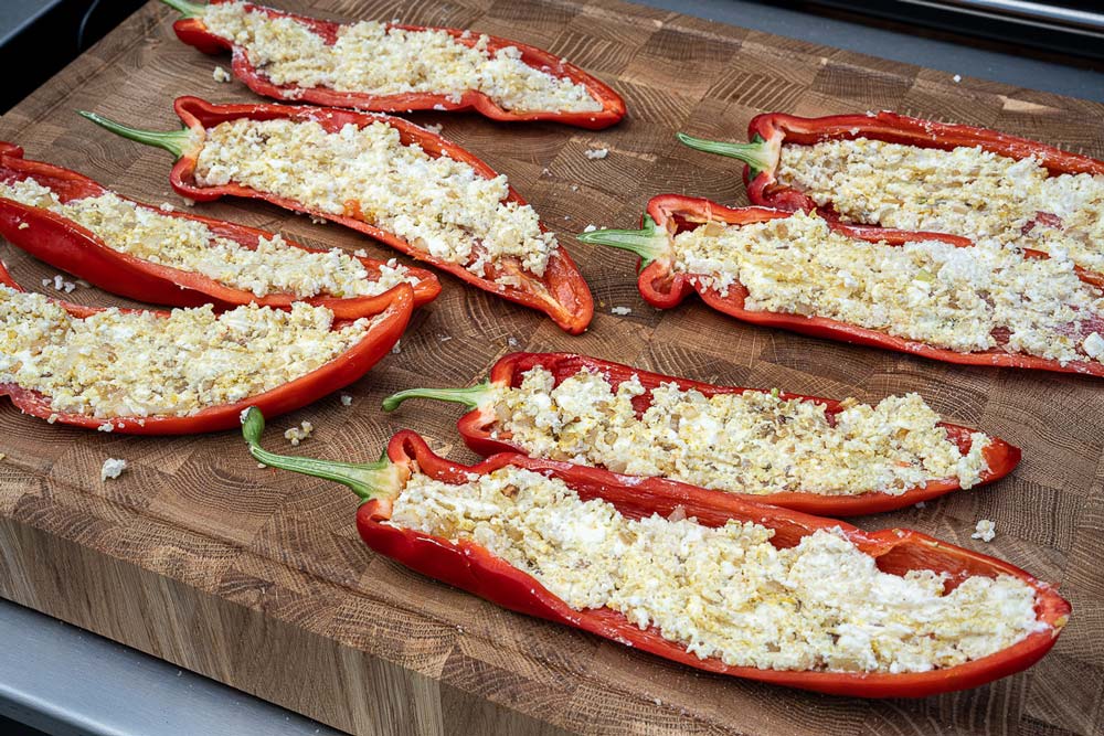 Die angeschwitzten Zwiebeln mit dem Frischkäse, dem Feta und dem
Couscous verrühren, anschließend mit Curry,
feinem Meersalz und gutem Pfeffer würzen. Im Anschluss
die Häften gleichmäßig mit der Masse füllen.