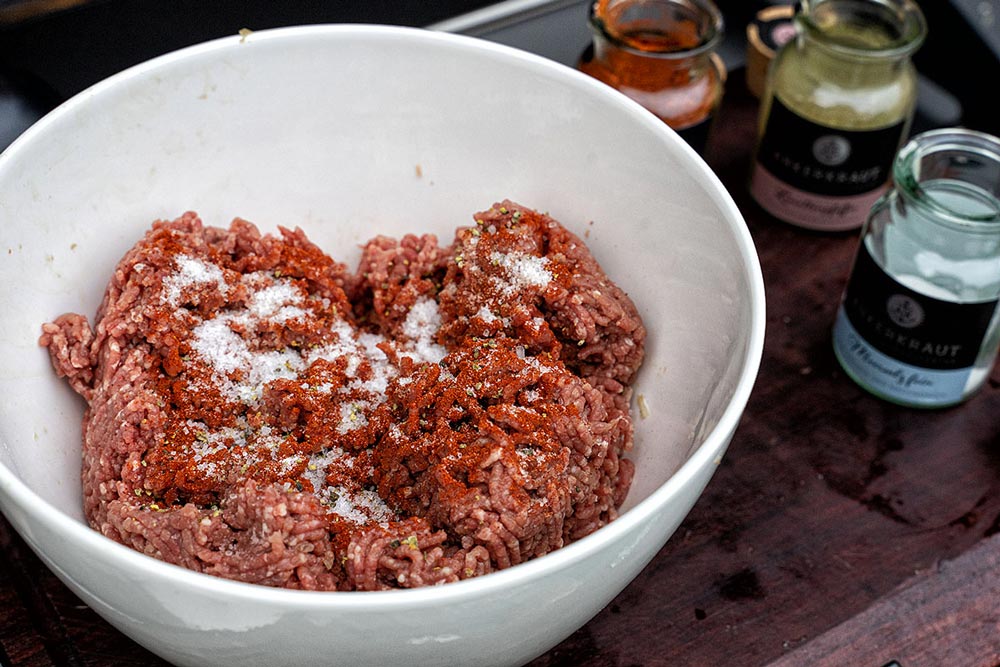 Das Gehackte mit feinem Meersalz, Paprika-Pulver und optional mit frisch gemahlenem schwarzen Pfeffer würzen.