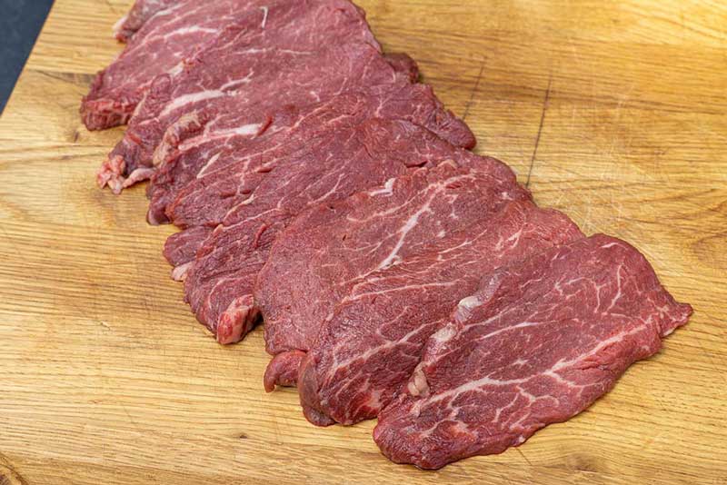 Rinderfilets liegen auf einem Holzbrett in der Küche, um die Raumtemperatur vor dem Grillen zu erreichen