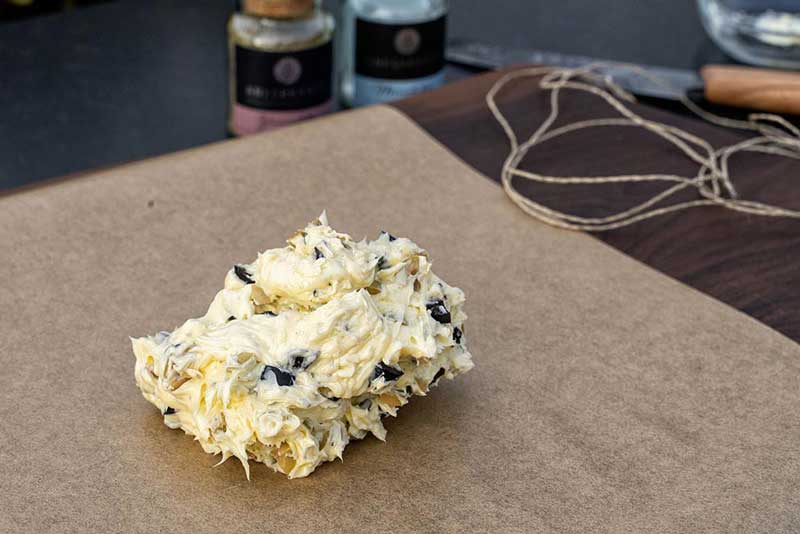 Die geachtelten Oliven unter die Butter heben,
mit Pfeffer und Meersalz würzen und anschließend auf Backpapier legen.